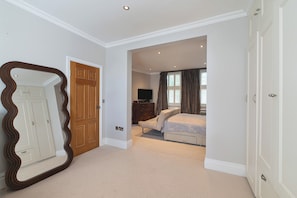 A bedroom with a large mirror, a bed, a dresser, and a door leading to another room. - Stylish Stockwell House with Garden & Comfort  - Pass the Keys (London)