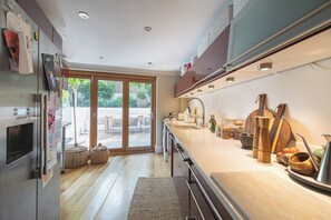 Eine moderne Küche mit großem Fenster, Holzschränken und diversen Küchengeräten.