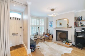 A living room with a fireplace, a piano, and a bookshelf. - Stylish Stockwell House with Garden & Comfort  - Pass the Keys (London)