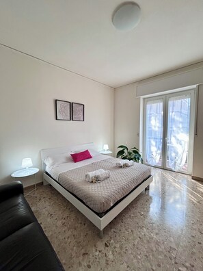 A bedroom with a bed, a nightstand, a chair, a window with curtains, and a plant. - Casa Gabry Verona | Ideal for families and groups (Verona)