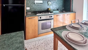 Uma cozinha com armários de madeira, geladeira preta, fogão e forno.