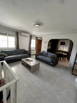 Ein modernes Wohnzimmer mit einer Couch, einem Couchtisch und einem Essbereich mit Tisch und Stühlen.