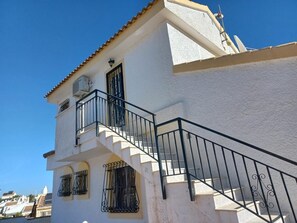 Ein weißes Gebäude mit Balkon und Treppe.
