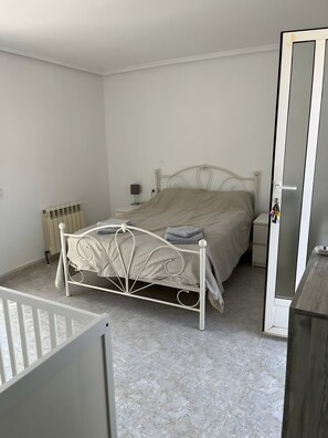 Un dormitorio con cama, mesita de noche, lámpara y radiador.