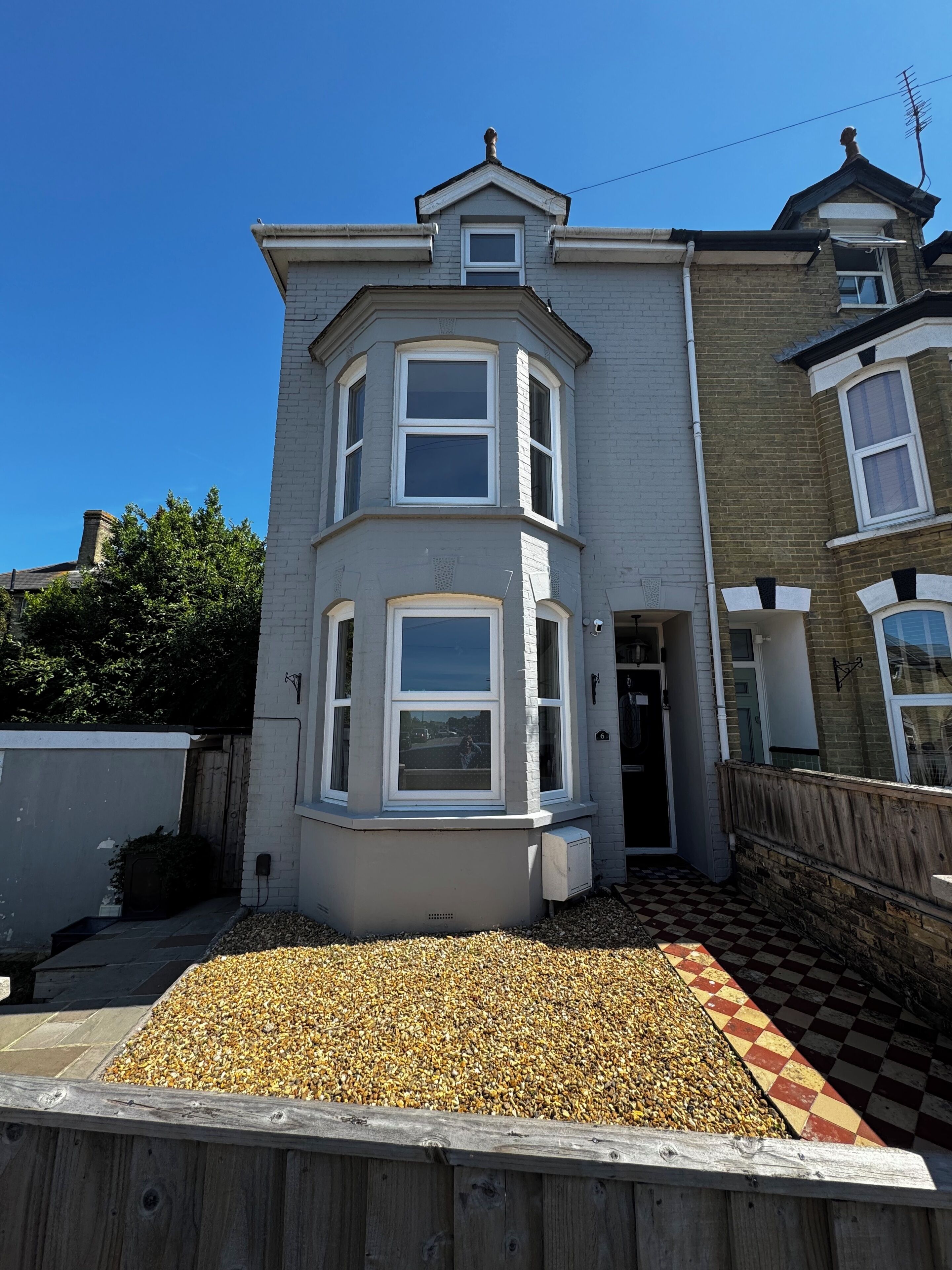 A two-story house with a bay window, a front door, and a small porch area.