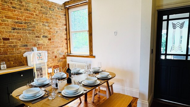A dining area with a brick wall, a window, and a door with a glass panel.