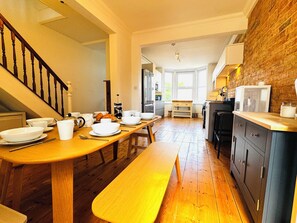 A kitchen with wooden flooring, a dining table with chairs, a bench, and a staircase. - Parley House , Cowes walk to Harbour Restaurants and Cafes (Cowes)