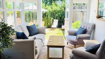 A conservatory with a sofa, armchairs, and a coffee table.