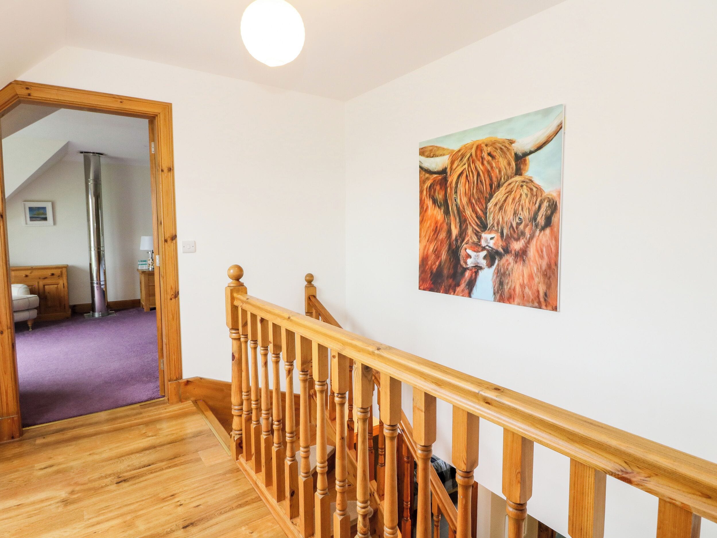 A wooden staircase with a railing, a painting of a bull on the wall, and a room with a purple carpet and wooden furniture.