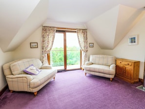 A room with two sofas, a wooden cabinet, and a large window with curtains. - Thistle Do (Lochailort)