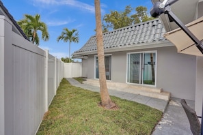 A residential property with a fenced yard, a palm tree, and a house with a tiled roof and sliding glass doors. - Luxury 6BR Villa Near Hollywood (Hollywood)
