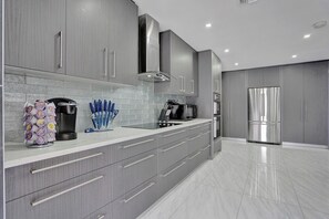 A modern kitchen with grey cabinetry, stainless steel appliances, and a coffee maker. - Luxury 6BR Villa Near Hollywood (Hollywood)