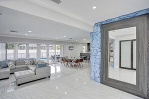 Amplia sala de estar con un sofá grande, una mesa de comedor y vistas a una piscina.