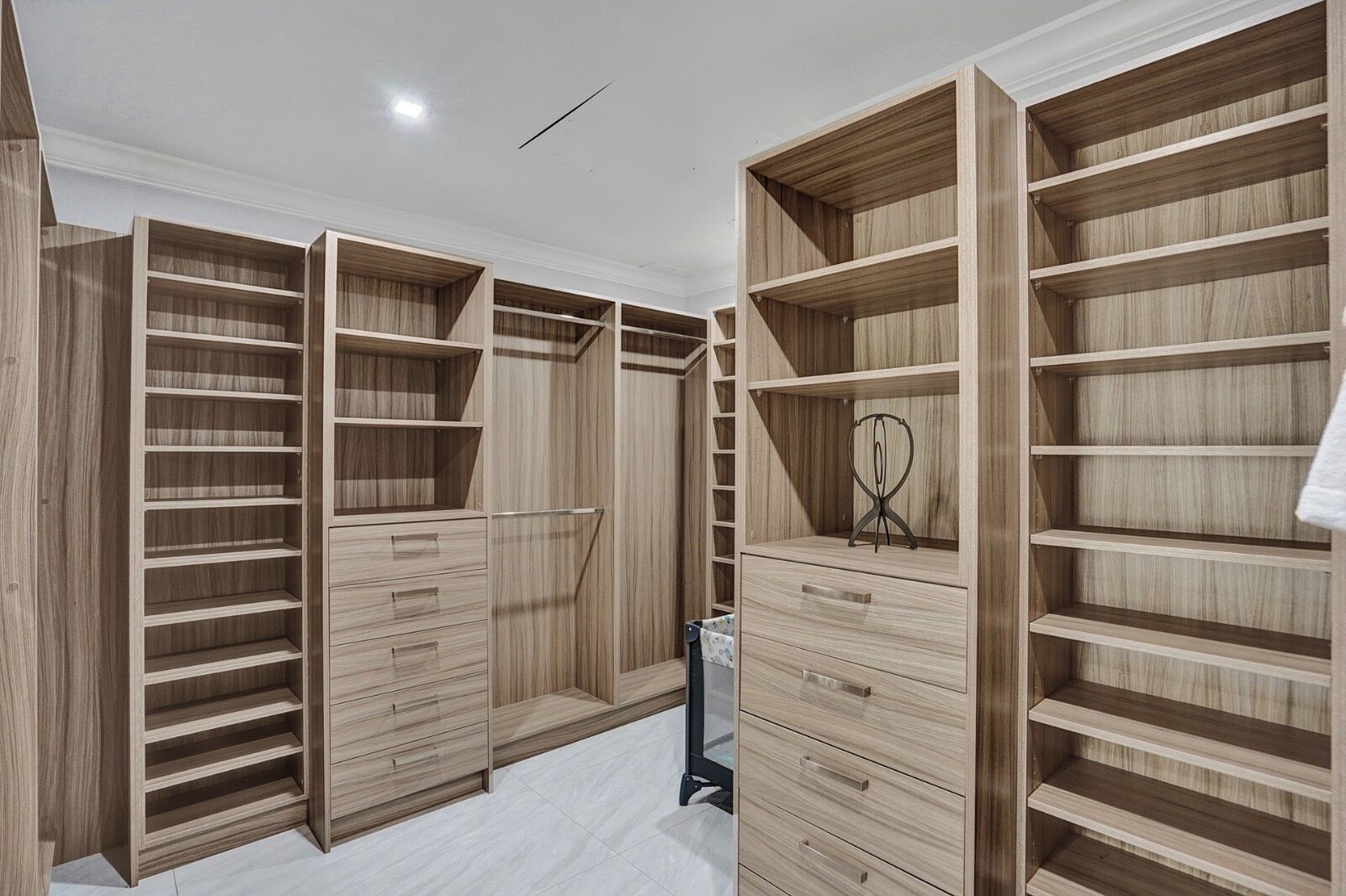 A walk-in closet with multiple wooden shelves and drawers.