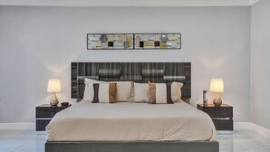 Ein modernes Schlafzimmer mit einem großen Bett, zwei Nachttischen mit Lampen und einem dekorativen Wandbild über dem Bett.