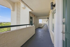 Ein Korridor mit einem Balkon, einer mit 'TREPPE' beschrifteten Tür und Blick ins Grüne.