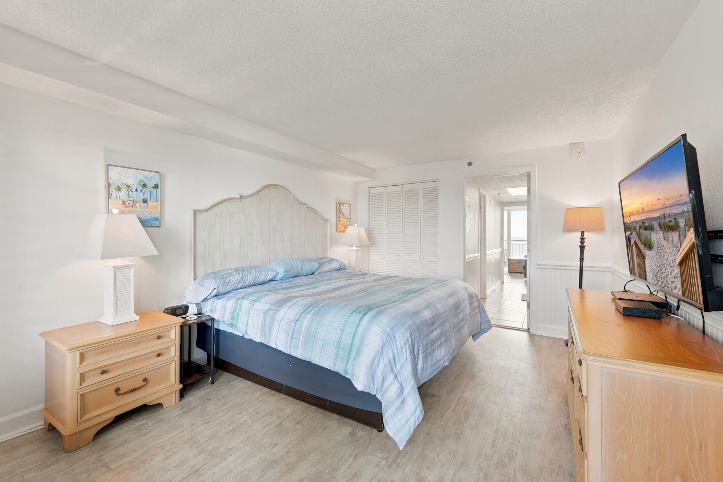Ein Schlafzimmer mit einem Bett, Nachttischen, einer Kommode und einem Fernseher.