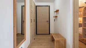 A hallway with wooden flooring, a central door, and a bench. - Prato - Terrace | Spa | Mtn views | Alpe d'Huez (Huez)