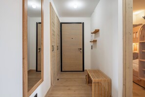 Ein Korridor mit Holzboden, einer zentralen Tür und einer Sitzbank.