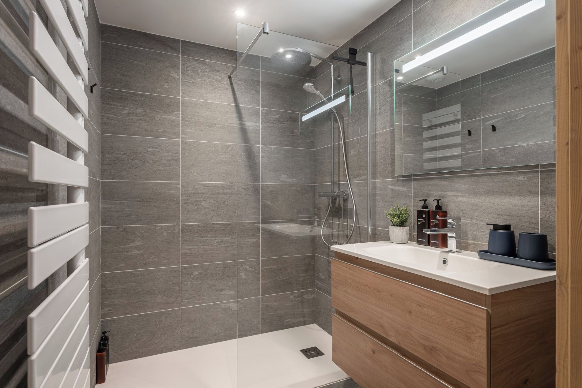 A modern bathroom with a shower, a vanity with a mirror, and a toilet.