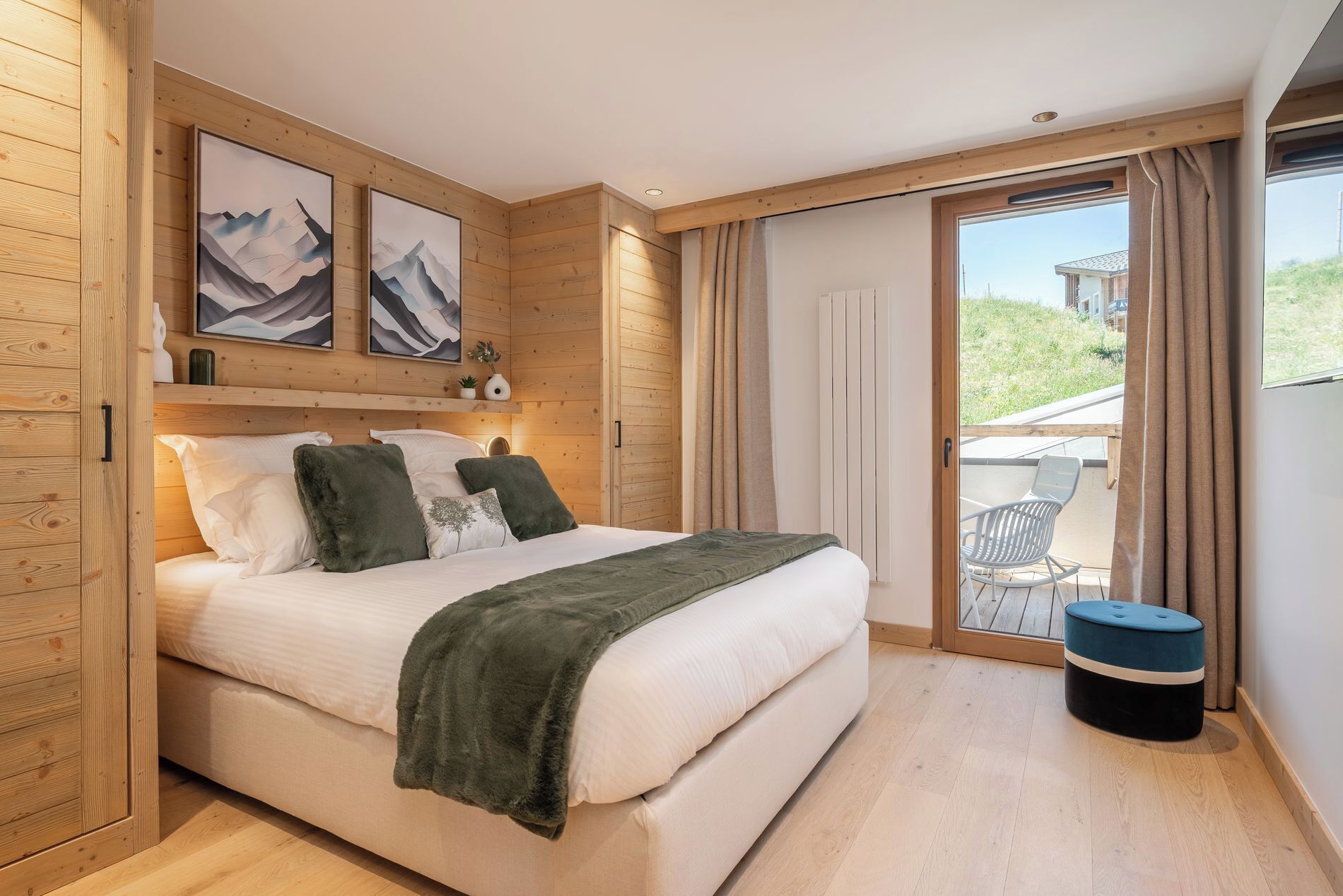 A bedroom with a bed, wooden paneling, a balcony with a chair, and a window.