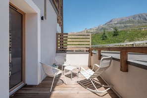 A balcony with a wooden railing, white chairs, and a table. - Altis - Terrace | Spa | Ski locker | Alpe d'Huez (Huez)