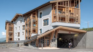 A multi-story building with a ski lift, wooden balconies, and a covered entrance. - Altis - Terrace | Spa | Ski locker | Alpe d'Huez (Huez)