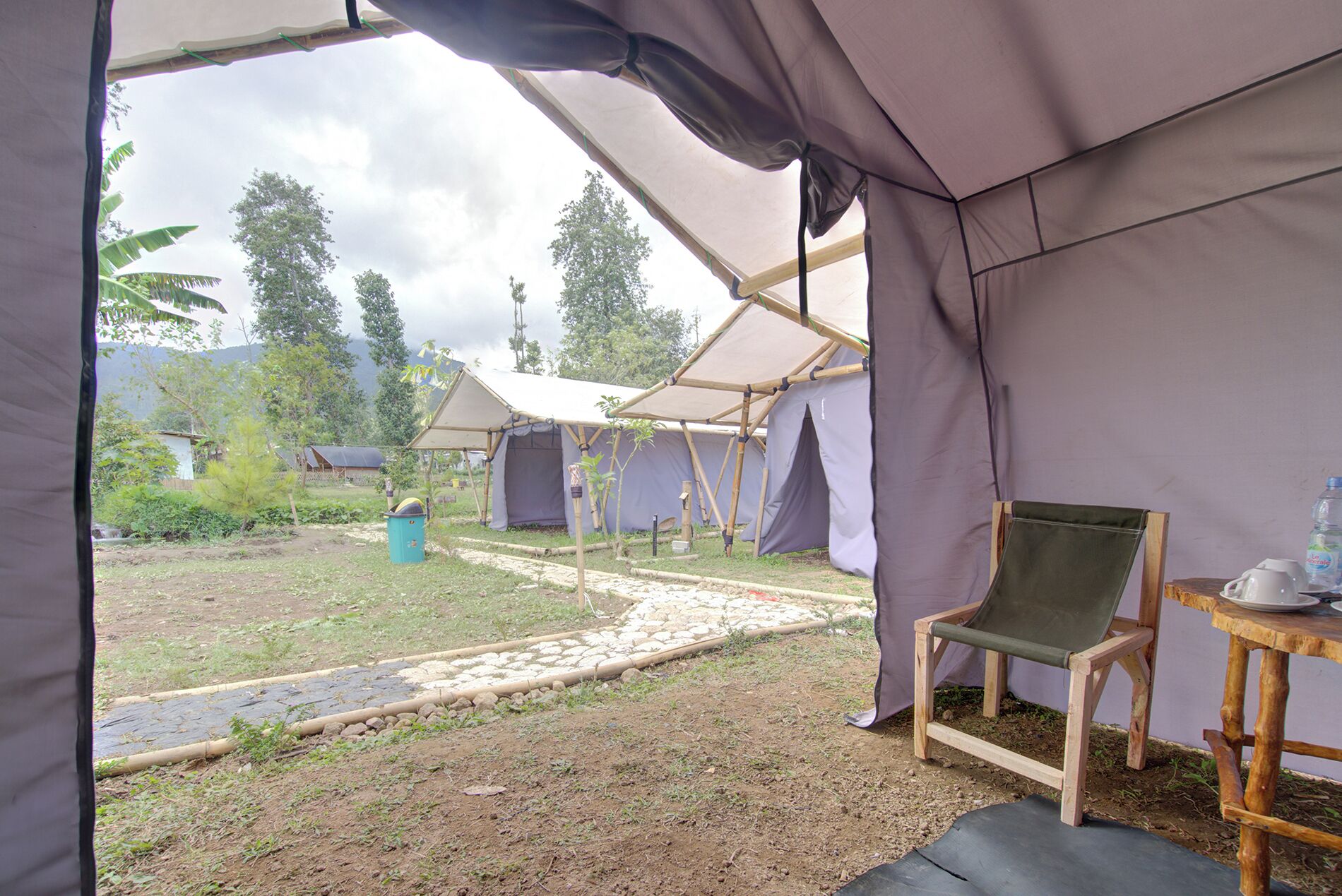 Un espacio con carpas que incluye una silla, una mesa, un sendero y otras carpas al fondo.