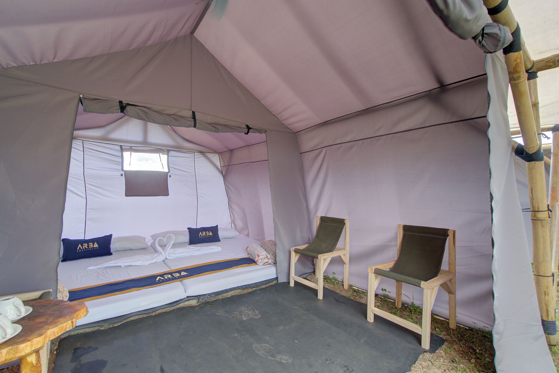 A tent with a bed, two chairs, and a small table.