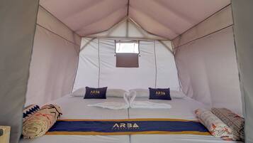 A tent-style room with a bed, pillows, and a blanket.