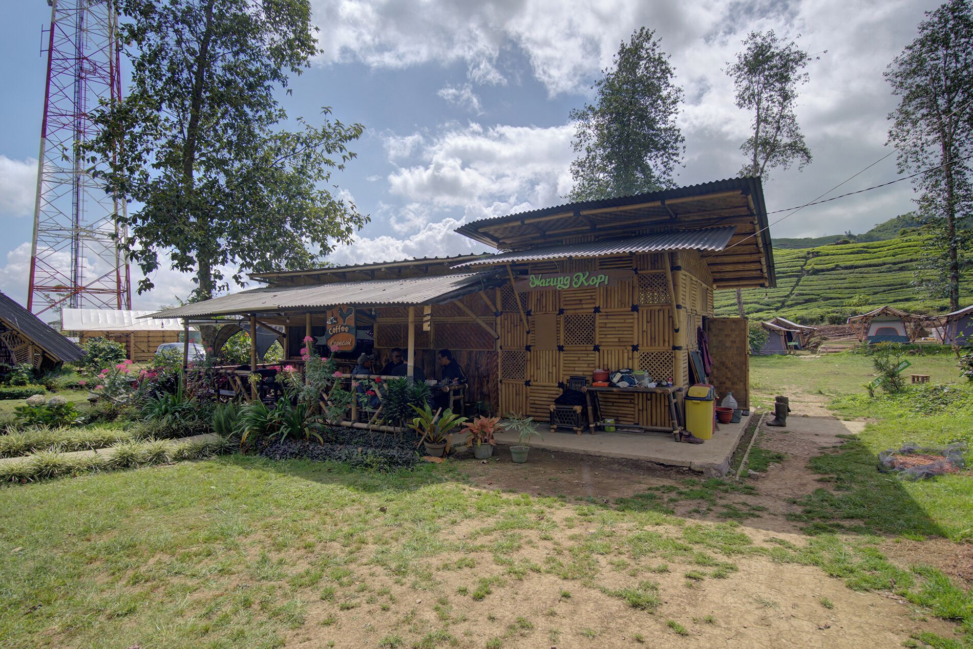 A rustic wooden building with a sign reading 'Coffee & Cacao' surrounded by lush greenery and terraced fields.