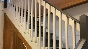 Una escalera de madera con barandas blancas y una barandilla oscura.