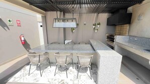 An outdoor kitchen area with a bar counter, seating, and a fire extinguisher. - 2-bedroom apartment w/ sunset view - Pool - Gym, beautiful Barranco y Miraflores (Lima)