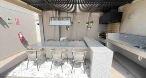 An outdoor kitchen area with a bar counter, seating, and a fire extinguisher. - 2-bedroom apartment w/ sunset view - Pool - Gym, beautiful Barranco y Miraflores (Lima)