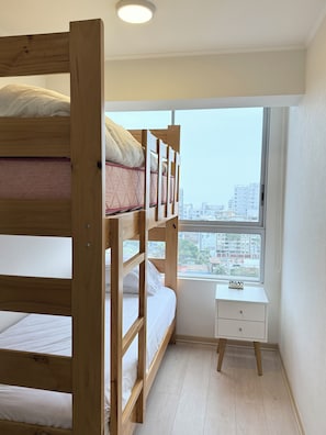 A bunk bed with a small bedside table and a window with a view of buildings. - Ocean View 2BR Pool & Gym Barranco-Miraflores (Lima)
