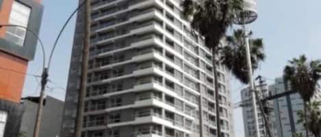 A high-rise building with multiple floors, surrounded by palm trees and other urban structures.