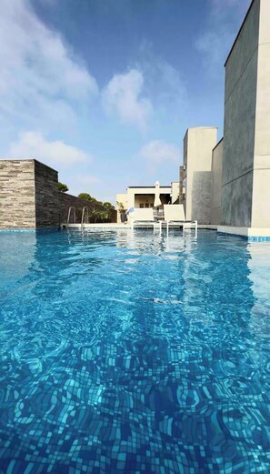 A swimming pool with clear blue water, surrounded by modern buildings and a clear sky. - 2-bedroom apartment w/ sunset view - Pool - Gym, beautiful Barranco y Miraflores (Lima)