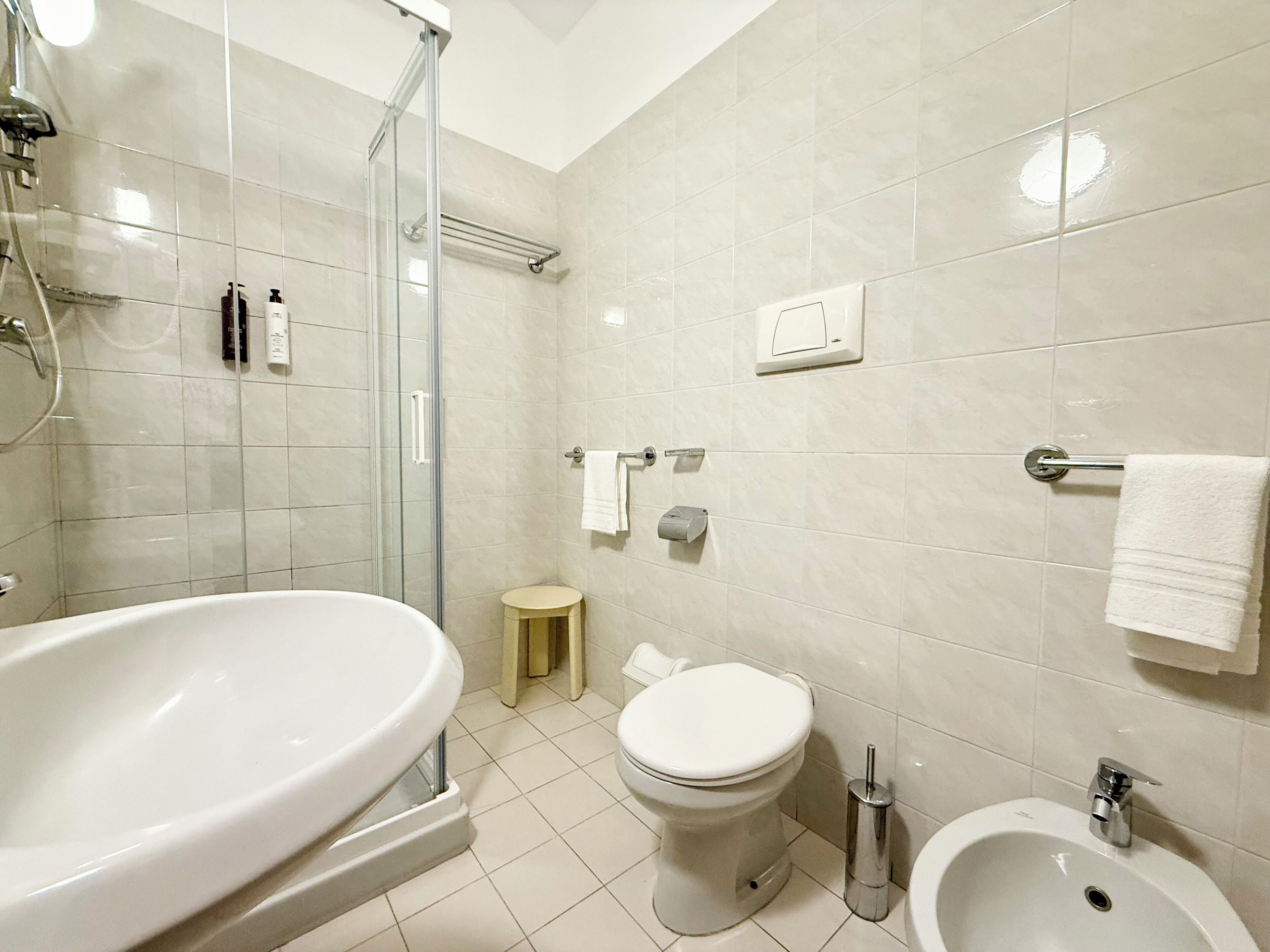 Un baño con ducha de vidrio, lavamanos blanco, inodoro y bidé.