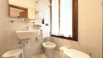 Une salle de bain moderne équipée d’un lavabo, de toilettes, d’un bidet et d’un miroir.