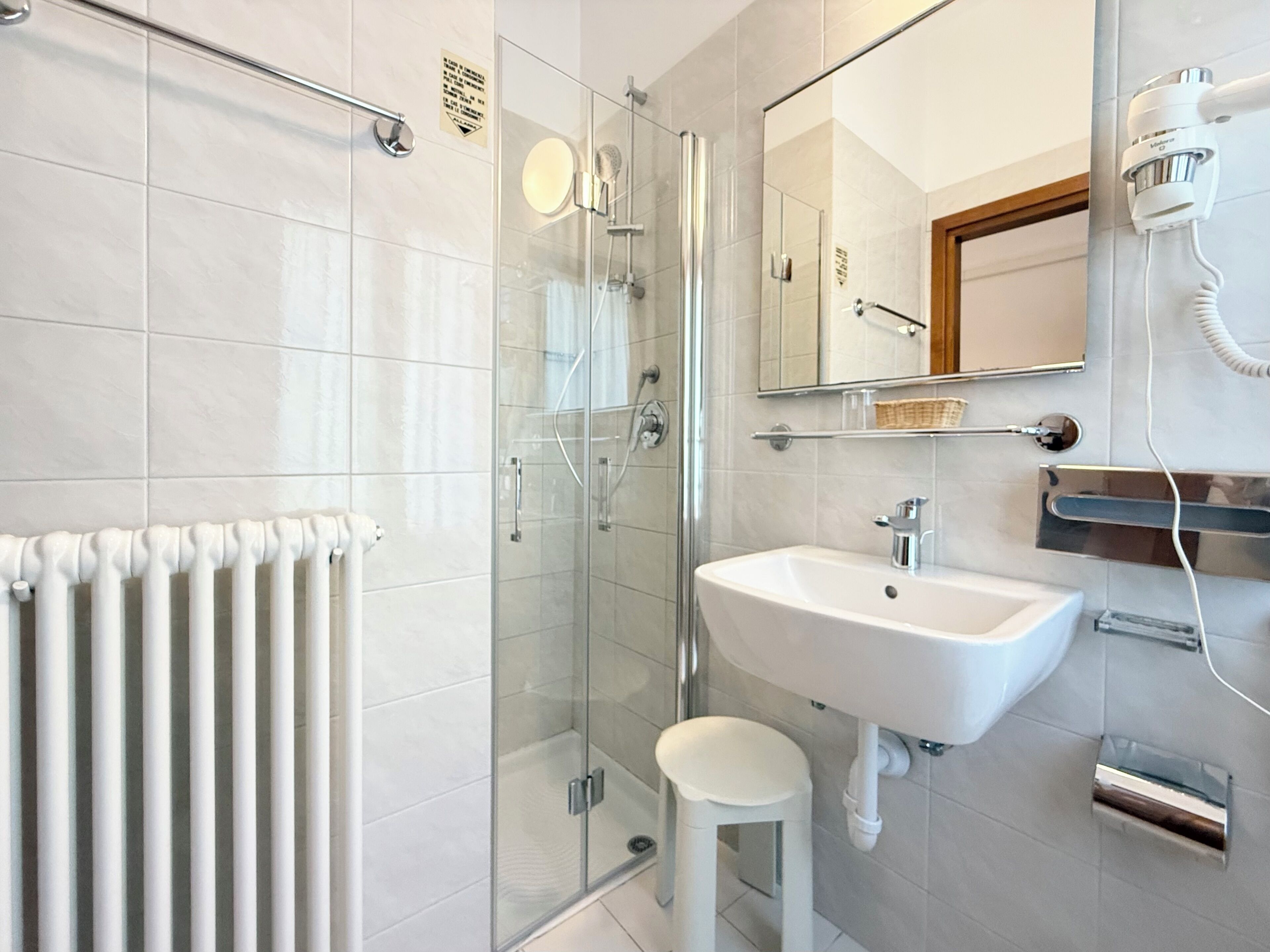 A modern bathroom with a glass shower enclosure, a white sink, and a mirror above the sink.