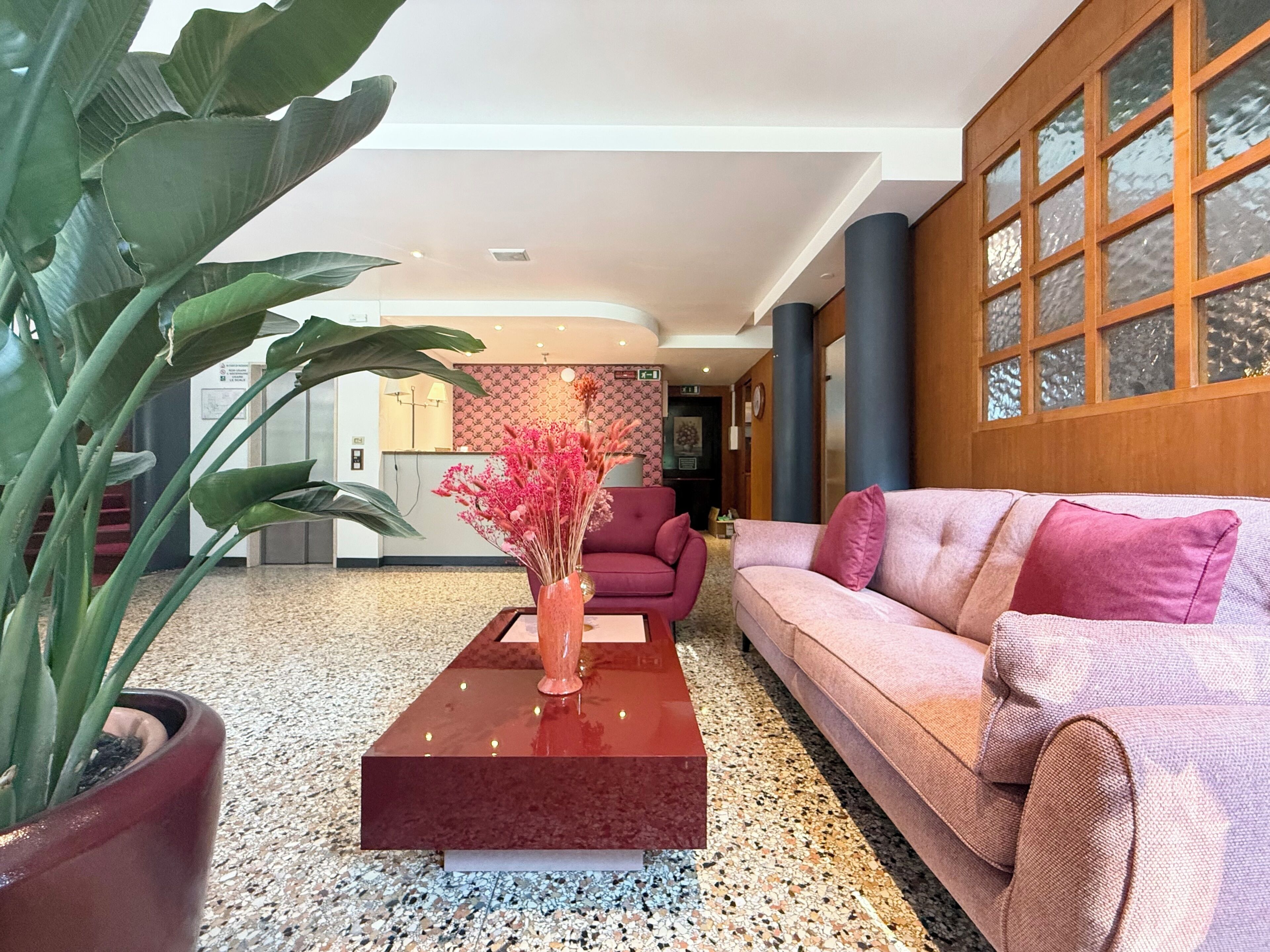 Eine moderne Lobby mit einem roten Sofa, einem Couchtisch und einer Zimmerpflanze.