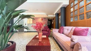 Eine moderne Lobby mit einem roten Sofa, einem Couchtisch und einer Zimmerpflanze.