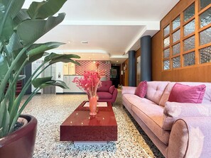 A modern lobby with a red sofa, a coffee table, and a potted plant. - HOTEL GRAN CASA (Oderzo)