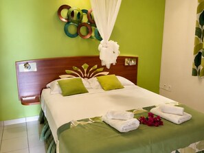 A hotel room with a bed, green pillows, a white canopy, and a wall decoration. - Villa Carbea (Saint François)