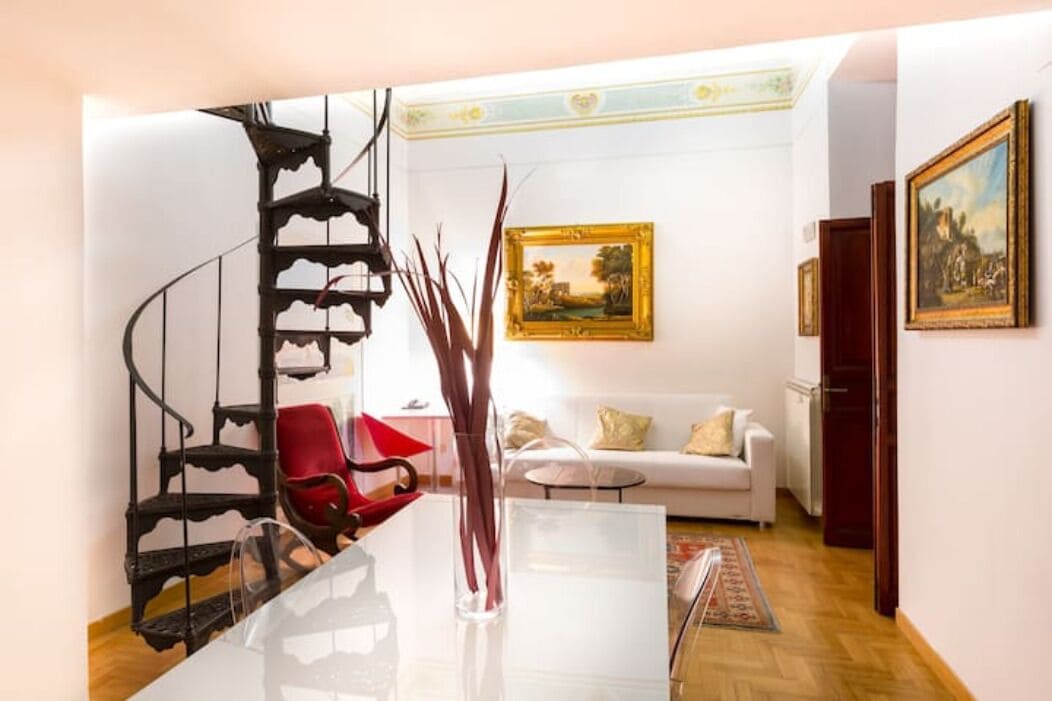 Una sala de estar moderna con una escalera en espiral, un sofá blanco y un cuadro en la pared.