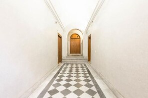 A hallway with a checkered floor and a wooden door at the end. - Rome Apartment Trevi Spagna Charme, Barberini Metro Station (Roma)