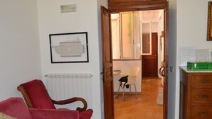 A room with a red armchair, a wooden dresser, and a framed picture on the wall. - Rome Apartment Trevi Spagna Charme, Barberini Metro Station (Roma)
