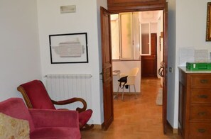 A room with a red armchair, a wooden dresser, and a framed picture on the wall. - Rome Apartment Trevi Spagna Charme, Barberini Metro Station (Roma)