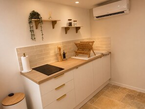 A modern kitchen with a wooden countertop, a built-in oven, and a wall-mounted air conditioner. - L'Escapade (Le Mans)