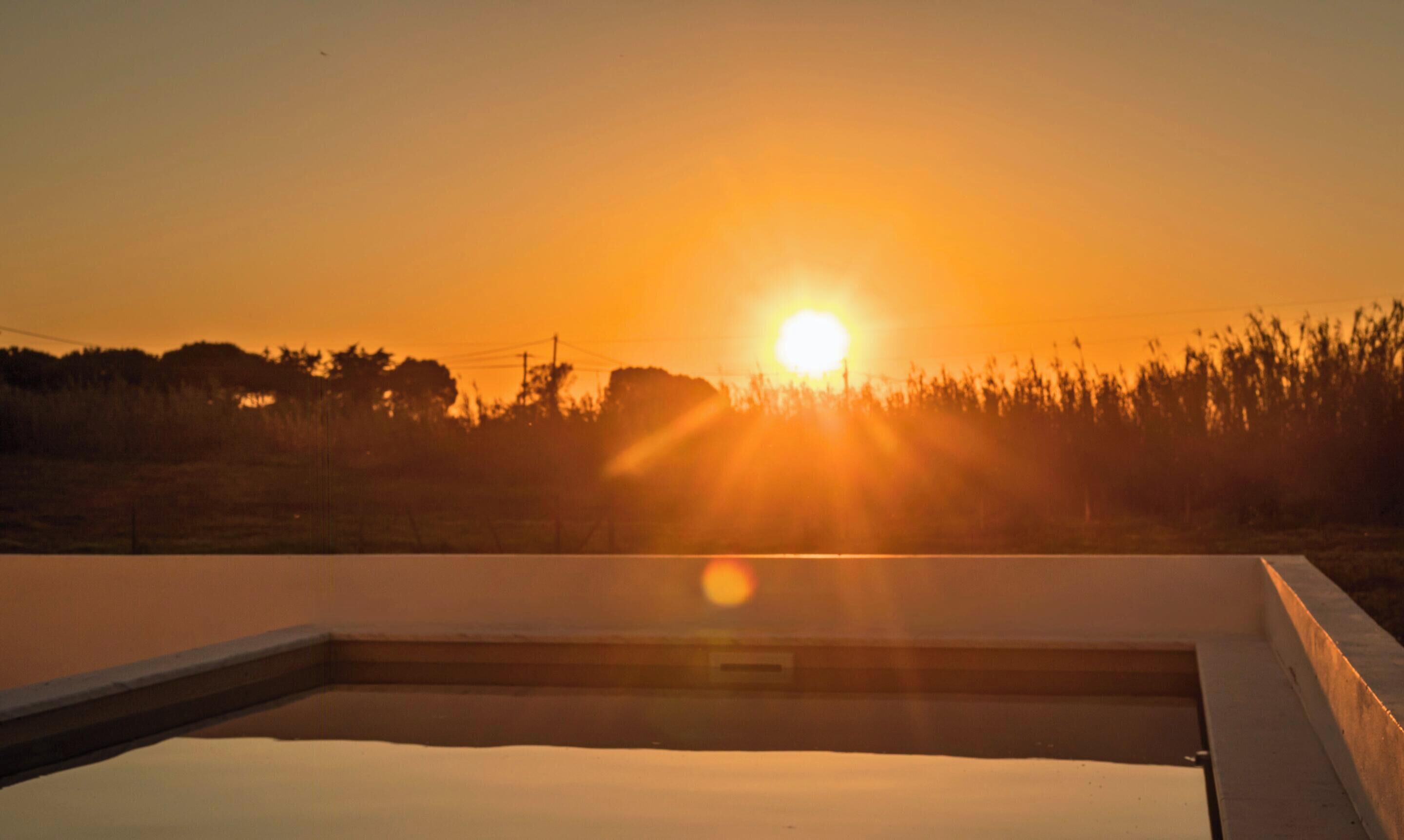 En swimmingpool med solnedgang i baggrunden.